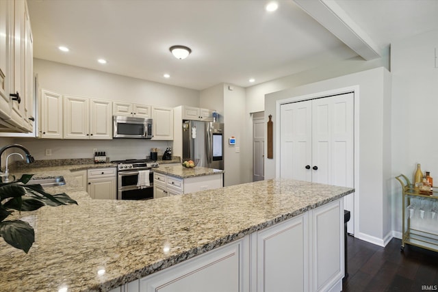 kitchen featuring stainless steel appliances, sink, light stone countertops, white cabinetry, and dark hardwood / wood-style flooring