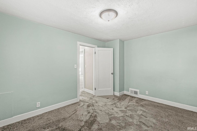 carpeted empty room featuring a textured ceiling