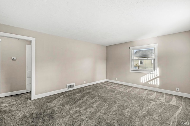 unfurnished room featuring a textured ceiling and dark colored carpet