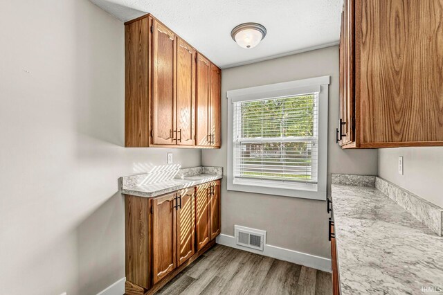 kitchen featuring light stone countertops, a textured ceiling, and light wood-type flooring