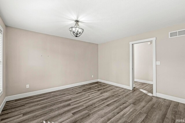 unfurnished room with hardwood / wood-style flooring and a chandelier