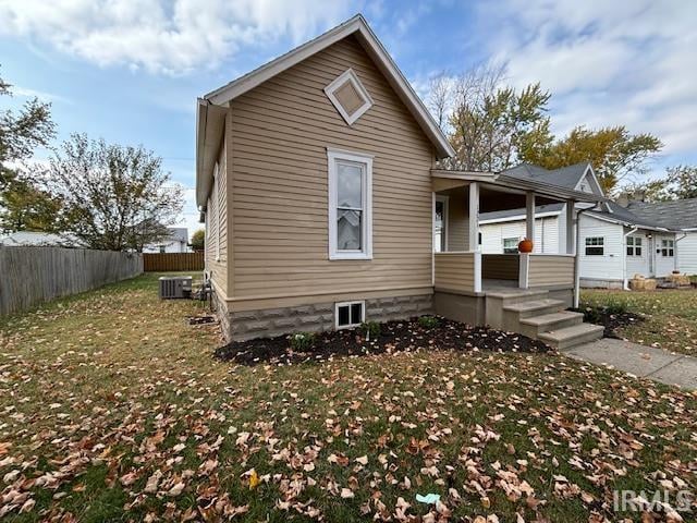 view of front of property featuring a front yard, cooling unit, and covered porch