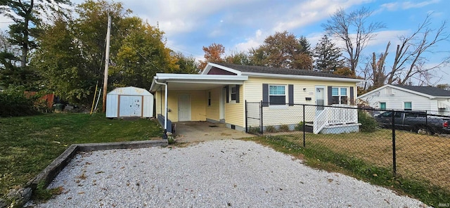 bungalow-style house featuring a carport, a storage unit, and a front lawn