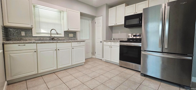 kitchen with appliances with stainless steel finishes, light tile patterned flooring, sink, white cabinets, and decorative backsplash