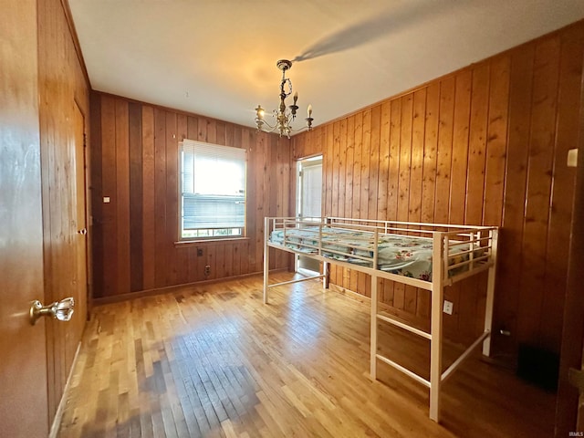 game room with an inviting chandelier, wooden walls, and wood-type flooring