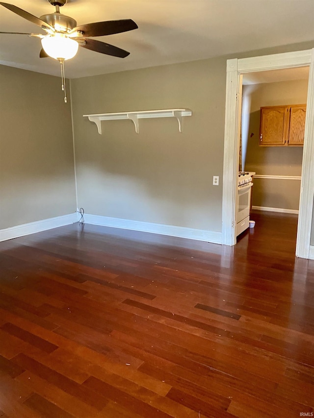 spare room with baseboards, ceiling fan, and dark wood-type flooring