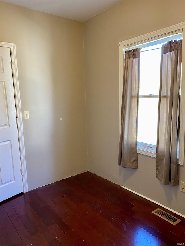 unfurnished room featuring dark wood-type flooring and visible vents