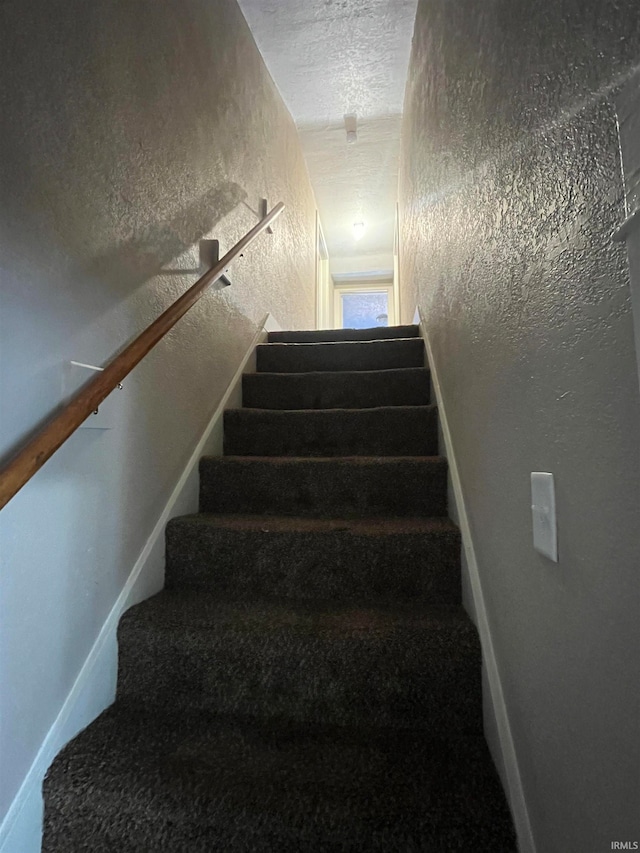 stairs featuring a textured ceiling