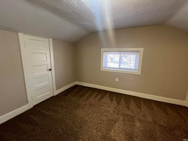 bonus room featuring vaulted ceiling, dark colored carpet, and a textured ceiling