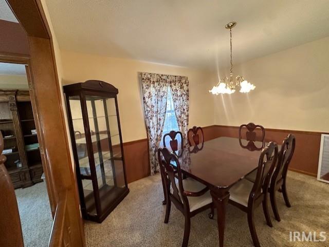 dining space featuring light colored carpet and a chandelier