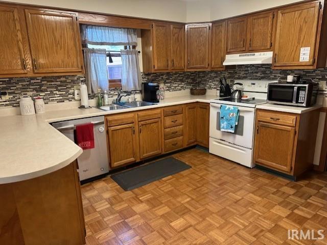 kitchen with stainless steel appliances, tasteful backsplash, sink, and light parquet floors