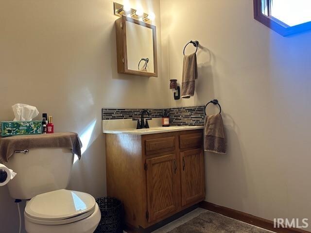 bathroom with vanity, decorative backsplash, and toilet