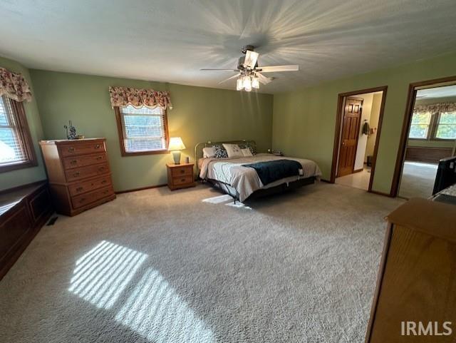 bedroom with ceiling fan, light colored carpet, and multiple windows