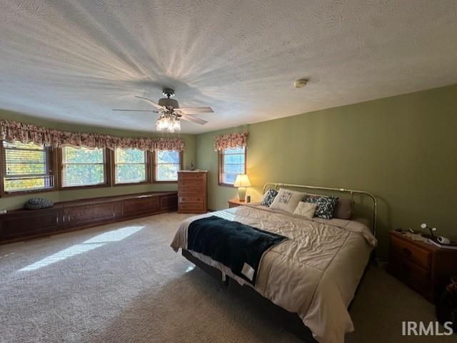 carpeted bedroom with ceiling fan and a textured ceiling