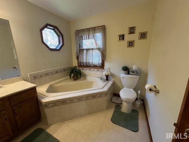 bathroom with vanity, tile patterned floors, tiled bath, and toilet