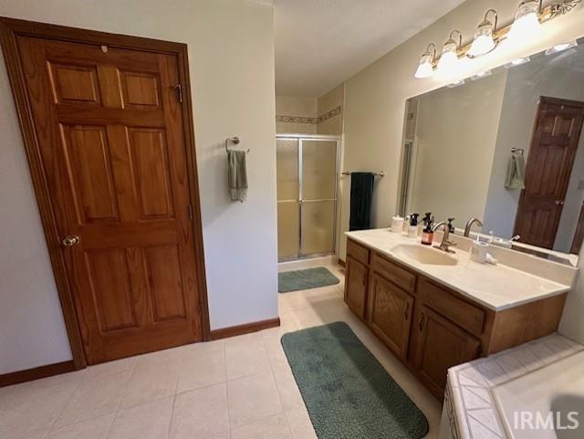 bathroom with walk in shower, tile patterned floors, and vanity