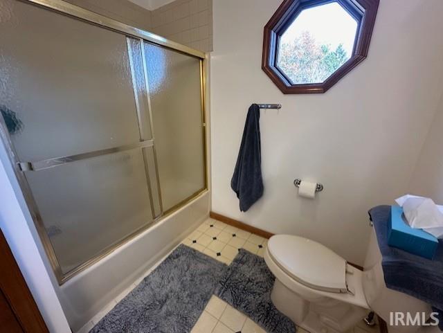 bathroom with combined bath / shower with glass door and toilet