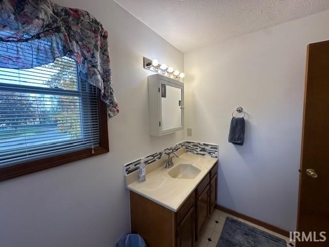 bathroom featuring tile patterned flooring, vanity, and a textured ceiling