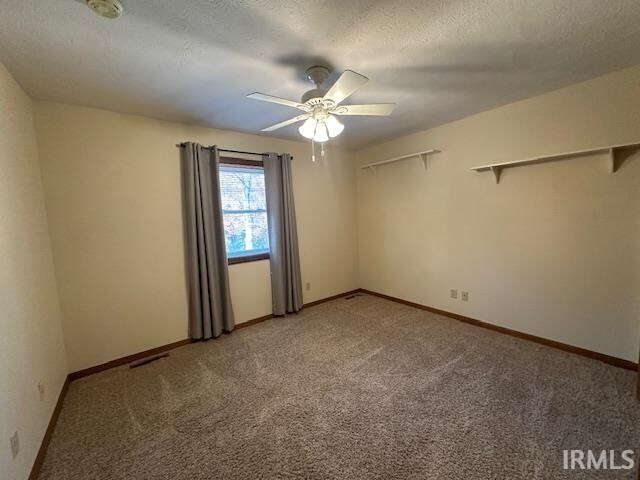 carpeted empty room with ceiling fan and a textured ceiling