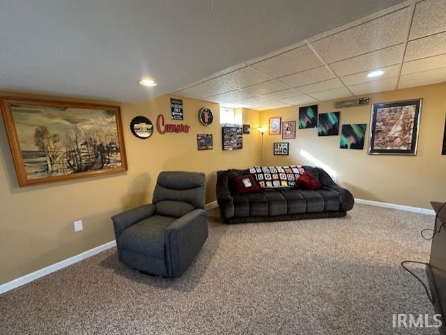 living room with a paneled ceiling and carpet flooring