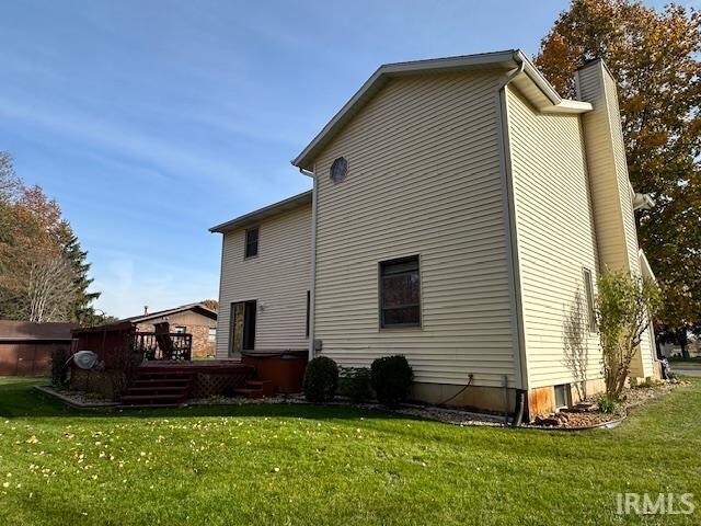 back of house featuring a wooden deck, a yard, and a hot tub