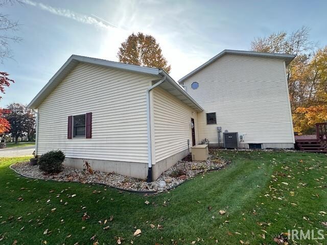 view of side of home featuring a yard and central AC