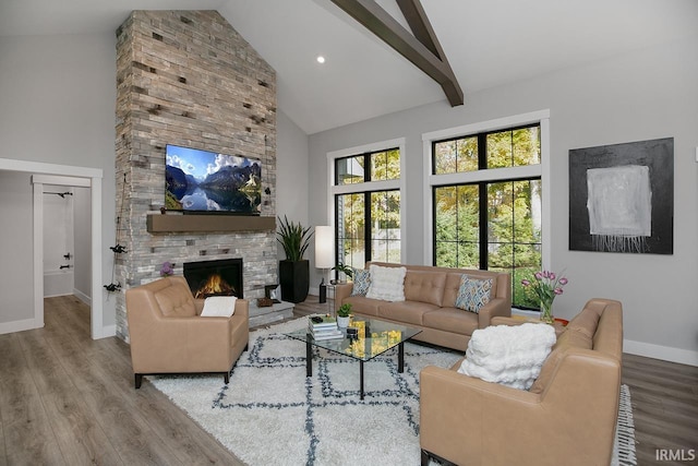 living room featuring high vaulted ceiling, a stone fireplace, beamed ceiling, and hardwood / wood-style floors