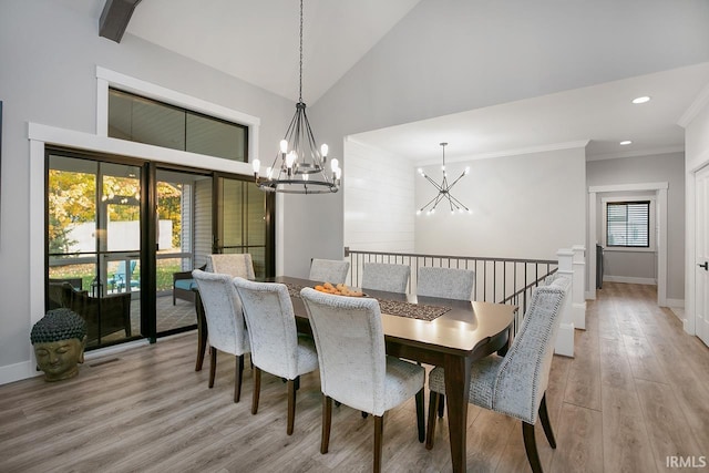 dining area with light hardwood / wood-style floors, high vaulted ceiling, an inviting chandelier, and plenty of natural light