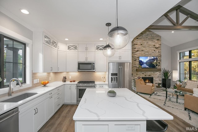 kitchen featuring a stone fireplace, stainless steel appliances, a kitchen island, and pendant lighting