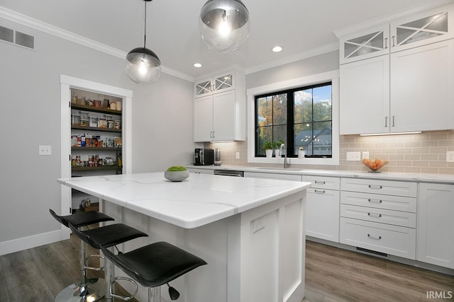 kitchen featuring dark hardwood / wood-style floors, sink, a center island, white cabinetry, and light stone counters