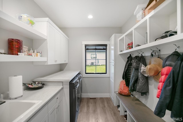 clothes washing area with sink, light hardwood / wood-style flooring, independent washer and dryer, and cabinets