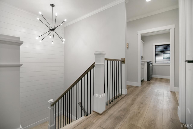 hall featuring an inviting chandelier, ornamental molding, and light wood-type flooring