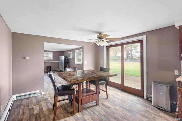 dining room with a baseboard heating unit, light wood-type flooring, and ceiling fan