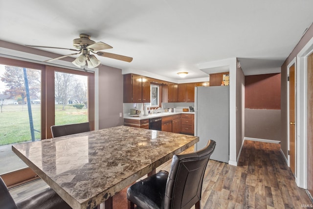 kitchen with dishwasher, a kitchen breakfast bar, hardwood / wood-style floors, white fridge, and ceiling fan