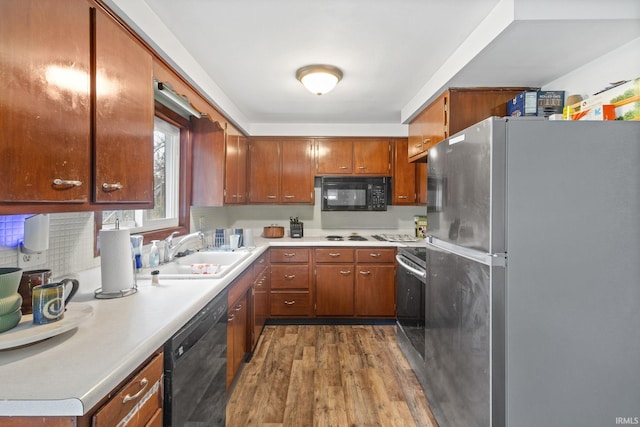 kitchen with sink, black appliances, decorative backsplash, and hardwood / wood-style flooring