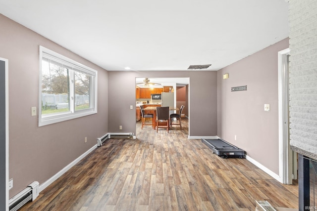 interior space featuring a baseboard heating unit, hardwood / wood-style floors, and ceiling fan