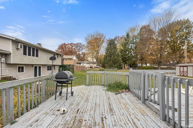 deck with a shed, a lawn, and a grill