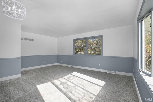 empty room with carpet floors, a chandelier, and plenty of natural light