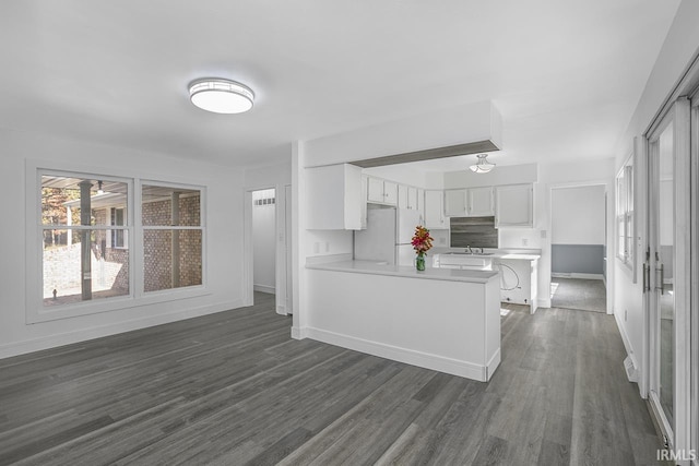 kitchen with dark hardwood / wood-style floors, kitchen peninsula, sink, white cabinets, and white fridge