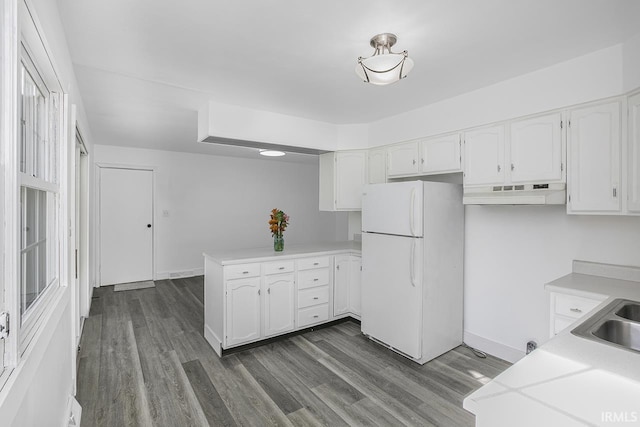 kitchen with sink, kitchen peninsula, white cabinetry, white refrigerator, and dark hardwood / wood-style floors