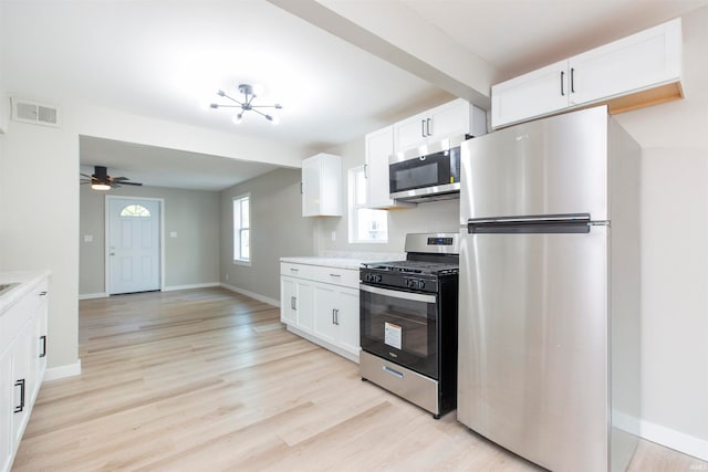 kitchen featuring stainless steel appliances, light hardwood / wood-style flooring, ceiling fan with notable chandelier, and white cabinets