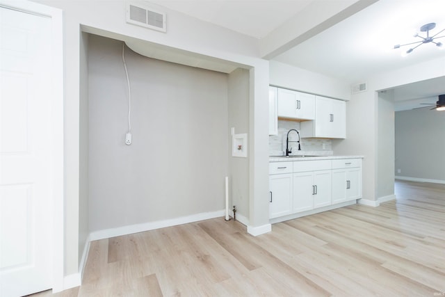 kitchen featuring sink, tasteful backsplash, white cabinetry, light hardwood / wood-style floors, and ceiling fan