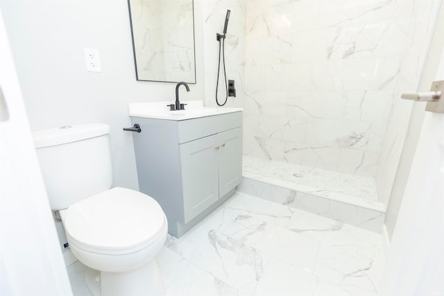 bathroom featuring toilet, vanity, and a tile shower