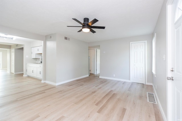 unfurnished room featuring a textured ceiling, light wood-type flooring, and ceiling fan