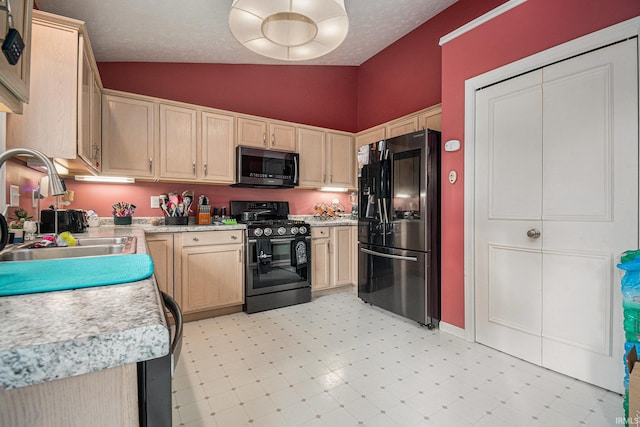 kitchen with light brown cabinets, sink, vaulted ceiling, and black appliances