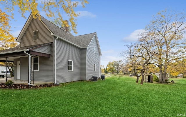 view of side of property with central AC unit and a lawn