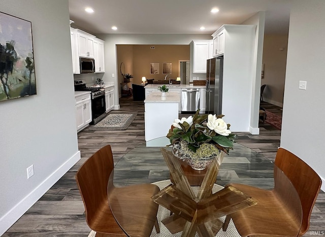 kitchen with dark wood-type flooring, white cabinets, kitchen peninsula, and stainless steel appliances