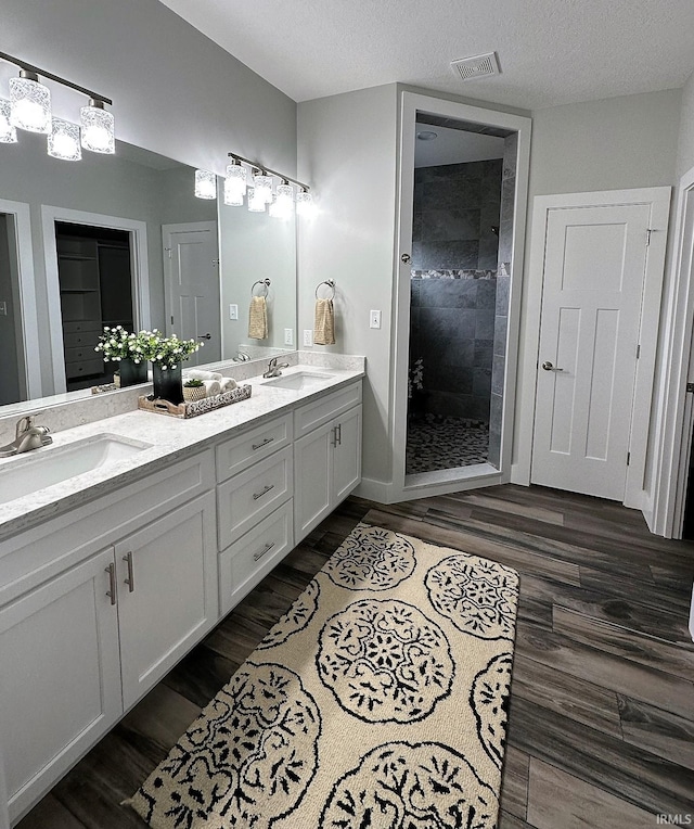 bathroom featuring vanity, a textured ceiling, tiled shower, and hardwood / wood-style floors