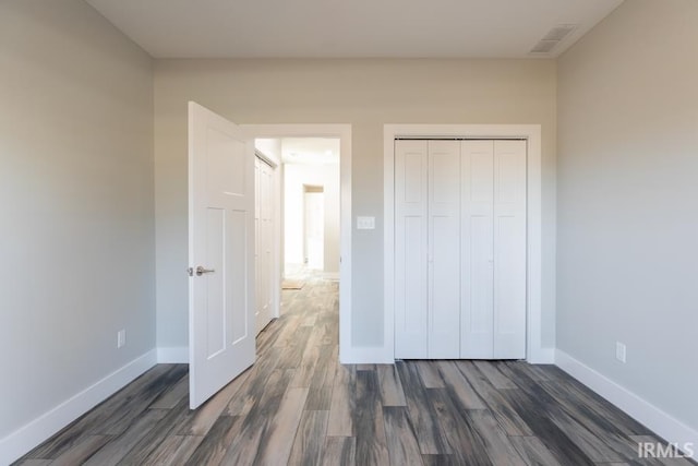 unfurnished bedroom with a closet and dark wood-type flooring