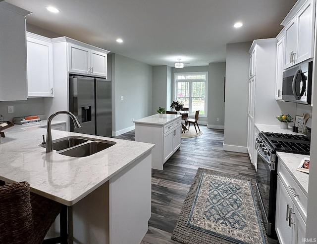 kitchen with white cabinetry, a center island, appliances with stainless steel finishes, and sink